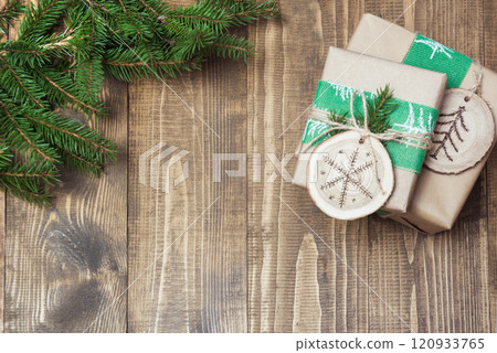 Christmas gift box in rustic style wrapped in craft paper with decor of wooden sliced with woodburning symbol. 120933765