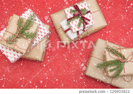 Christmas gift box wrapped in ornament paper and decorative red rope ribbon on red surface. Creative hobby, top view. Prepare to Xmas. Banner. 120933822