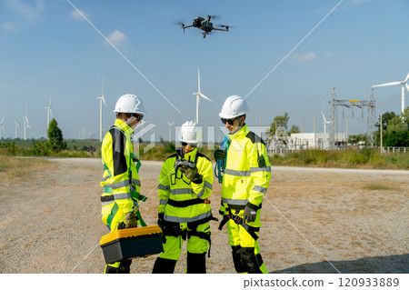 Wind turbine or windmill worker woman or technician control drone to work with her co-worker team in workplace field during day time. Wind turbine or windmill worker woman or technician control drone to work with her co-worker team in workplace field during day time. 120933889