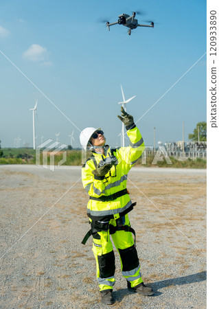 Vertical image wind turbine or windmill worker woman or technician control drone to work in workplace field during day time. Vertical image wind turbine or windmill worker woman or technician control drone to work in workplace field during day time. 120933890