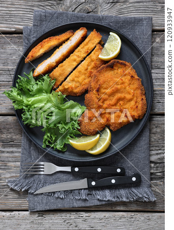 Pork Milanese with lettuce and lemon on a plate 120933947