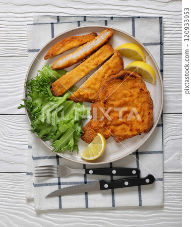 Pork Milanese with lettuce and lemon on a plate 120933953