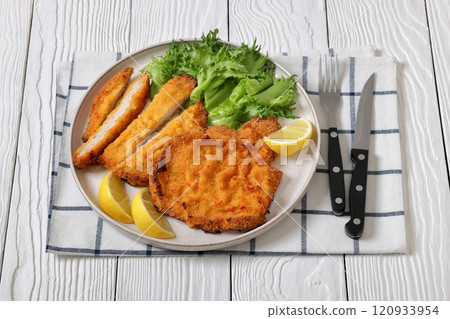 Pork Milanese with lettuce and lemon on a plate 120933954