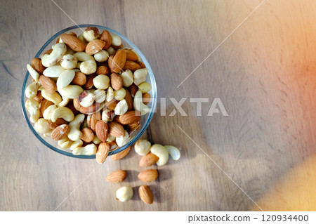 Cashews, peanuts and almonds on a plate. Nuts on the table in the bright rays of the sun. Cashews, peanuts and almonds on a plate. Nuts on the table in the bright rays of the sun. 120934400