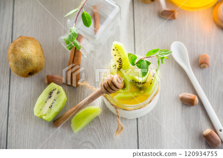 Homemade yogurt in a glass jar with honey, kiwi, nuts. 120934755