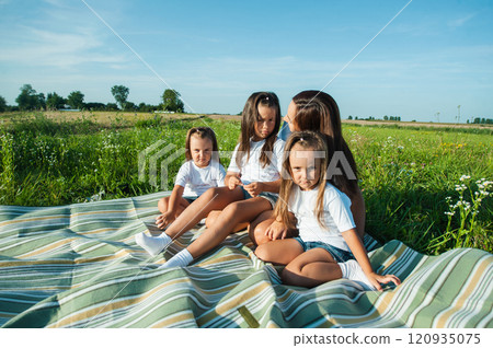 A mother and her daughters are having fun in a field. A mother and her daughters are having fun in a field. 120935075
