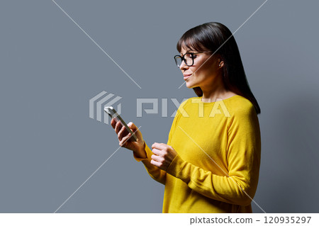Profile view middle aged woman using smartphone on grey background 120935297