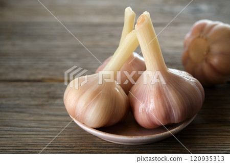A few heads of pickled garlic. Salted garlic in a plate on kitchen table with copy space. A few heads of pickled garlic. Salted garlic in a plate on kitchen table with copy space. 120935313