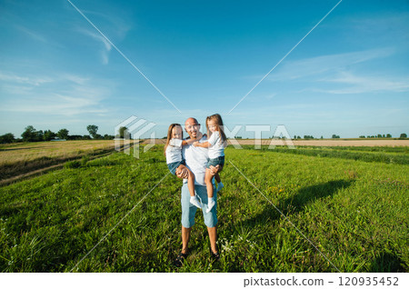 Dad having fun with pretty daughters in nature on sunset. 120935452