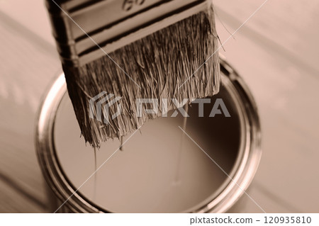 Close-up of paintbrush dipped in a can on wooden surface 120935810