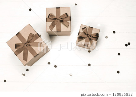 Elegant gift boxes with brown ribbons on a light wooden surface 120935832