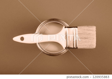 Paintbrush resting on open paint can in a neutral shade background Paintbrush resting on open paint can in a neutral shade background 120935863