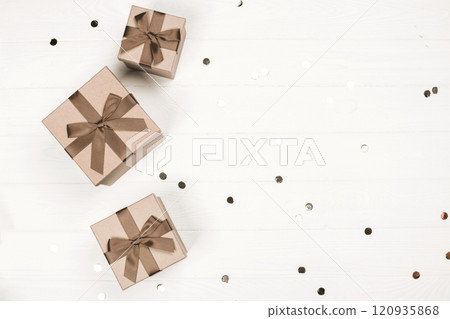 Elegant gift boxes with brown ribbons on a white wooden background Elegant gift boxes with brown ribbons on a white wooden background 120935868