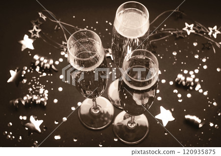 Celebratory champagne glasses among festive decorations in vintage sepia tone 120935875