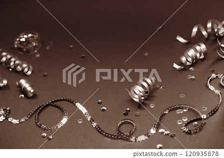 Festive ribbons and sequins on a moody brown background for celebration Festive ribbons and sequins on a moody brown background for celebration 120935878