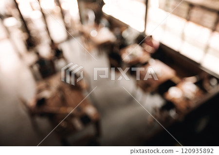 Blurred view of a cozy cafe interior with warm lighting and wooden tables 120935892