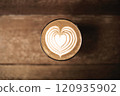 Heart-shaped latte art on coffee table viewed from above 120935902