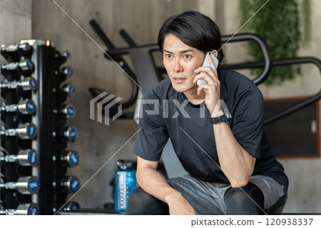年輕的亞洲男子在健身房用智慧型手機交談 120938337