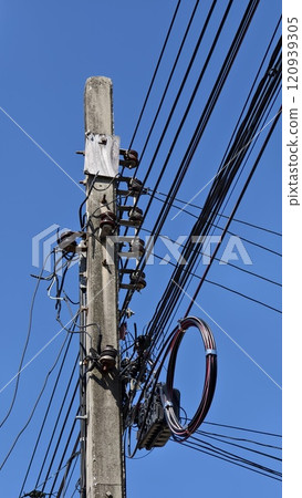 Close-up of roadside electric pole with blue sky in the background. 120939305