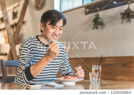 Middle-aged man eating pasta, spaghetti, noodles, carbohydrates in a cafe or restaurant 120939964