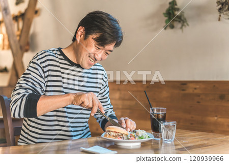 中年男子在咖啡館/餐廳吃漢堡/垃圾食品 120939966