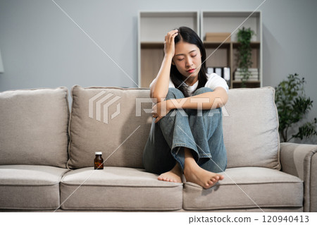 woman sit Depression Dark haired  pensive glance Standing by window on sofa and anxiety 120940413