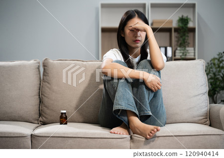 woman sit Depression Dark haired pensive glance Standing by window on sofa and anxiety woman sit Depression Dark haired pensive glance Standing by window on sofa and anxiety 120940414