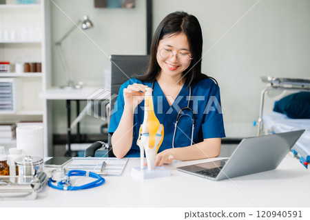 Confident young female doctor in white medical uniform sit at desk working on computer. Smiling use laptop Confident young female doctor in white medical uniform sit at desk working on computer. Smiling use laptop 120940591