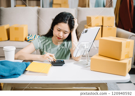 Asian owner woman prepare parcel box  woman is stressed, bored, and overthinking from working and standing check online orders for deliver to customer. 120940592