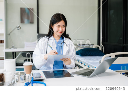 Confident young female doctor in white medical uniform sit at desk working on computer. Smiling use laptop Confident young female doctor in white medical uniform sit at desk working on computer. Smiling use laptop 120940643