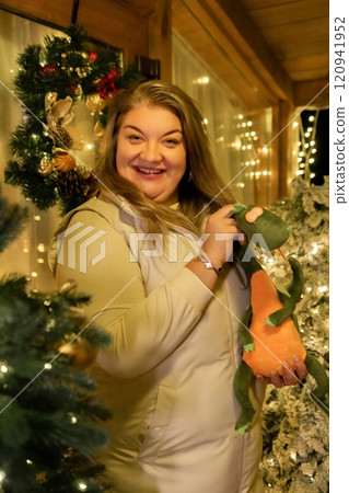 Woman Christmas Decorations Holiday Cheer - A woman smiles near Christmas decorations in her home. 120941952
