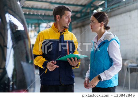 Claim or insurance agent inspecting the accident vehicle in garage and taking with woman client. Professional claim - insurance concept. 120942949