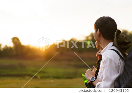 Happy Asian men looking at the beautiful sunlight during the sunset behind mountain together. Friends touch - hold hands together. Happy Asian men looking at the beautiful sunlight during the sunset behind mountain together. Friends touch - hold hands together. 120943105