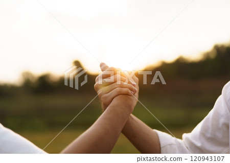 Happy Asian men looking at the beautiful sunlight during the sunset behind mountain together. Friends touch - hold hands together. 120943107