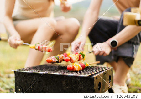 Group of Asian people enjoy grille a meat barbecue - BBQ together during their camping at the park in spring or summer. Weekend and holiday activity concept. 120943108