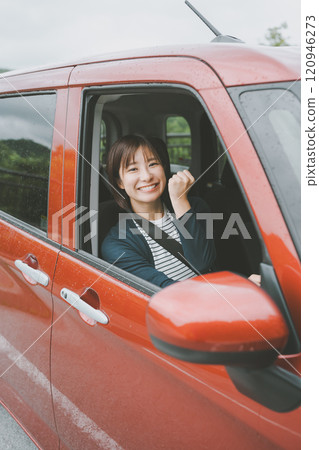 A smiling young woman in a car gives a thumbs up A smiling young woman in a car gives a thumbs up 120946273