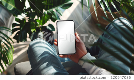 Phone mockup in hand. Smartphone with empty display. Living room background. Cellphone showing copyspace. White screen with copy space. Blank mobile for mock up 120947086