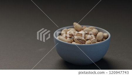 salted pistachios in blue bowl on black background salted pistachios in blue bowl on black background 120947743