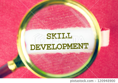 Business concept. The conceptual phrase SKILL DEVELOPMENT written on through a magnifying glass under torn paper 120948900