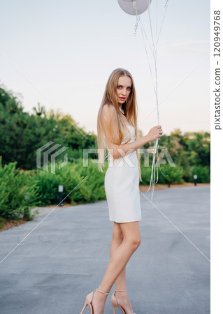 Beautiful slender blonde with long hair and balloons in an evening park. Beautiful slender blonde with long hair and balloons in an evening park. 120949768