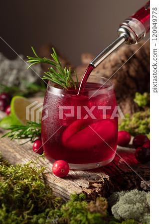 Cranberry cocktail with ice, lime, and rosemary on a old wooden board. Cranberry cocktail with ice, lime, and rosemary on a old wooden board. 120949778