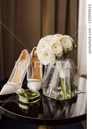A stylish wedding. bridal bouquet, perfume and shoes on the table.  120949818