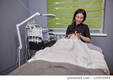 Female Specialist, Skin Health, Female Masseuse. SPF sunscreen is meticulously applied to patient's face by skincare specialist. 120950989