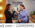 Cosmetologist Salon, Brow Stylist, Salon Mirror. Client in beauty salon gets to see outcome her eyebrow correction as cosmetologist specialist holds mirror up for her. 120950992