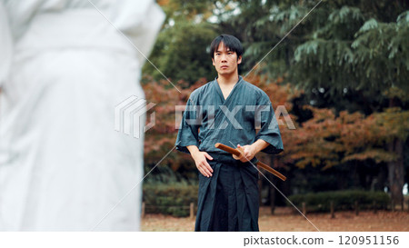 Sword, martial arts and man in outdoor training with culture, fight coaching or samurai challenge in park. Wooden weapon, warrior and Japanese people sparring in nature for traditional bokken battle. Sword, martial arts and man in outdoor training with culture, fight coaching or samurai challenge in park. Wooden weapon, warrior and Japanese people sparring in nature for traditional bokken battle. 120951156