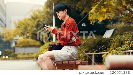 Phone, reading and relax with Japanese man in college for student portal, education and University website. Social media, networking and research with person on campus for streaming and chat 120951388