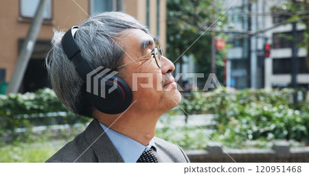 Business, headphones and thinking with mature man outdoor in city for break from job or work. Idea, music and vision with corporate Japanese employee outdoor in urban town for future or planning 120951468