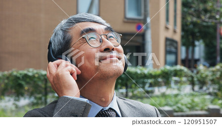 Business, music and thinking with mature man outdoor in city for break from job or work. Headphones, idea and vision with corporate Japanese employee outdoor in urban town for future or planning 120951507