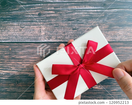 Woman's hands untying the ribbon on a gift 120952213