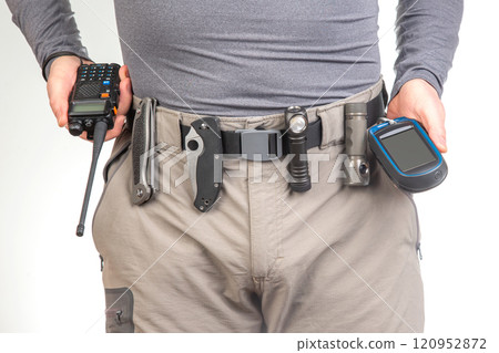 walkie-talkie, flashlight, knife on the belt of the tourist trekking pants 120952872